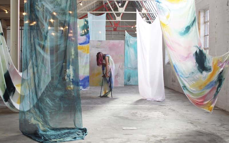 BA Fine Art work by Brooke Savino showing an installation view of a dancer amongst painted fabrics.