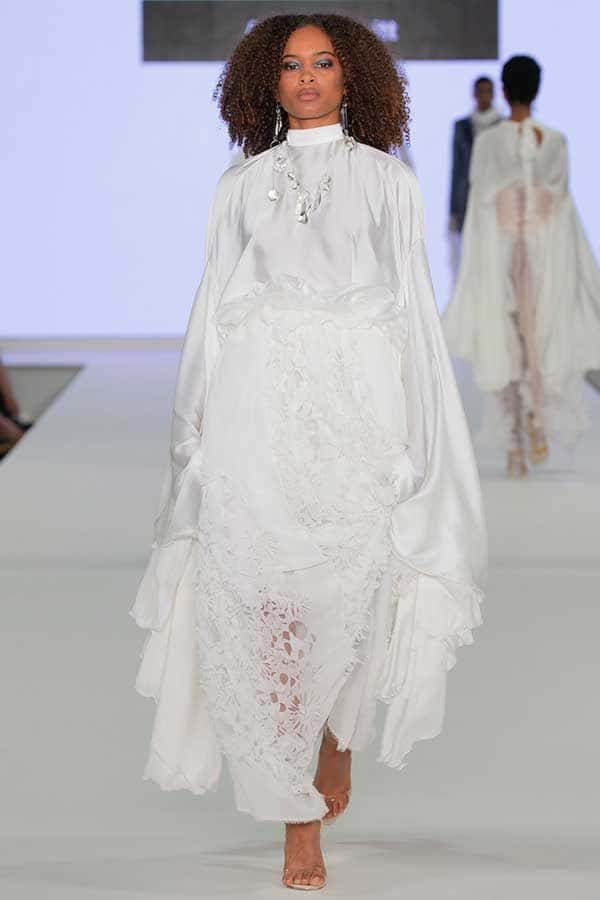 Amelia Nevitt - Image of a model wearing and white dress with detailed lace and draping