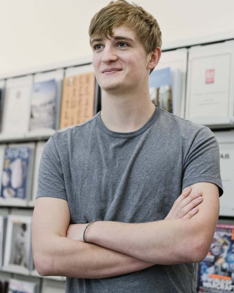 portrait photo of alum edd mitchem smiling and looking away from camera with crossed arms, short hair and wearing a grey t-shirt