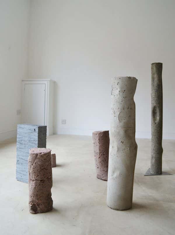  - photo of white room with concrete pillars of varying irregular shapes and consistencies standing in the centre