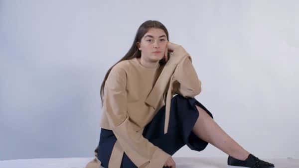 Sophie Chittock - Image of a female model sitting on the floor, looking to camera wearing tailored garments