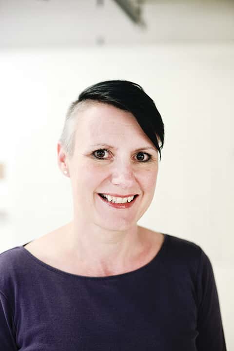 portrait photo of senior lecturer Sarah Horton smiling at camera with cropped black hair and a dark blue top