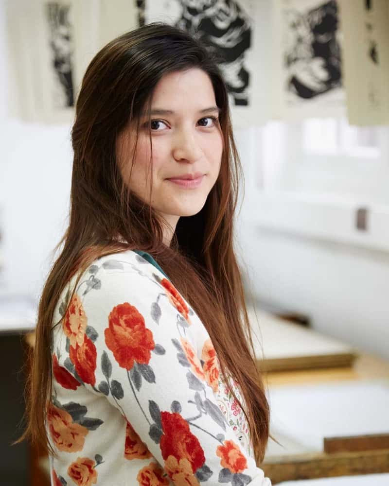 portrait photo of alum Karla Alcazar Martinez smiling and looking off screen with medium length hair in loose floral top