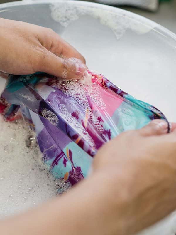  - Image of a sudent washing material which has been dyed bright colours