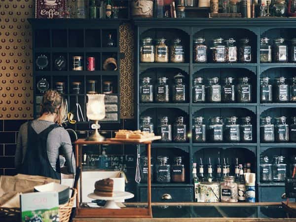 Biddys Tea Room, Norwich - Image of various jars of tea lines up on a blue vintage shelving unit inside a cafe