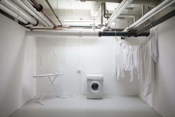  - Installation from BA Degree Show 2017 of a white washing machine, ironing board and hanging clothes in a white space