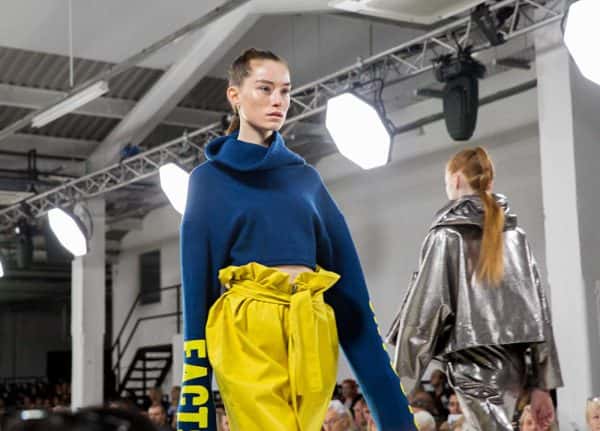 Meg Tovery - Image of a model wearing a blue jumper and yellow trousers on the catwalk at Graduate Fashion Week