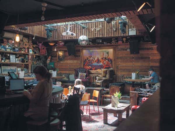 Gonzos Tea Room - Image of people sat in a bar which featuring wooden walls and large paintings, plants and contemporary seating
