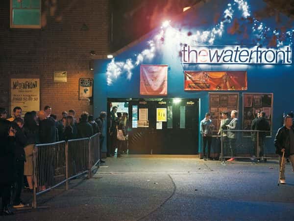 The Waterfront Music Venue - Image of the exterior of a blue building featuring a lighted sign with the title The Waterfront