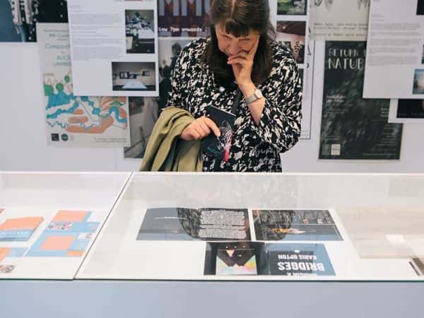 MA Curation - Image of a female visitor looking in a vintrine of publications at the MA Degree Show 2017