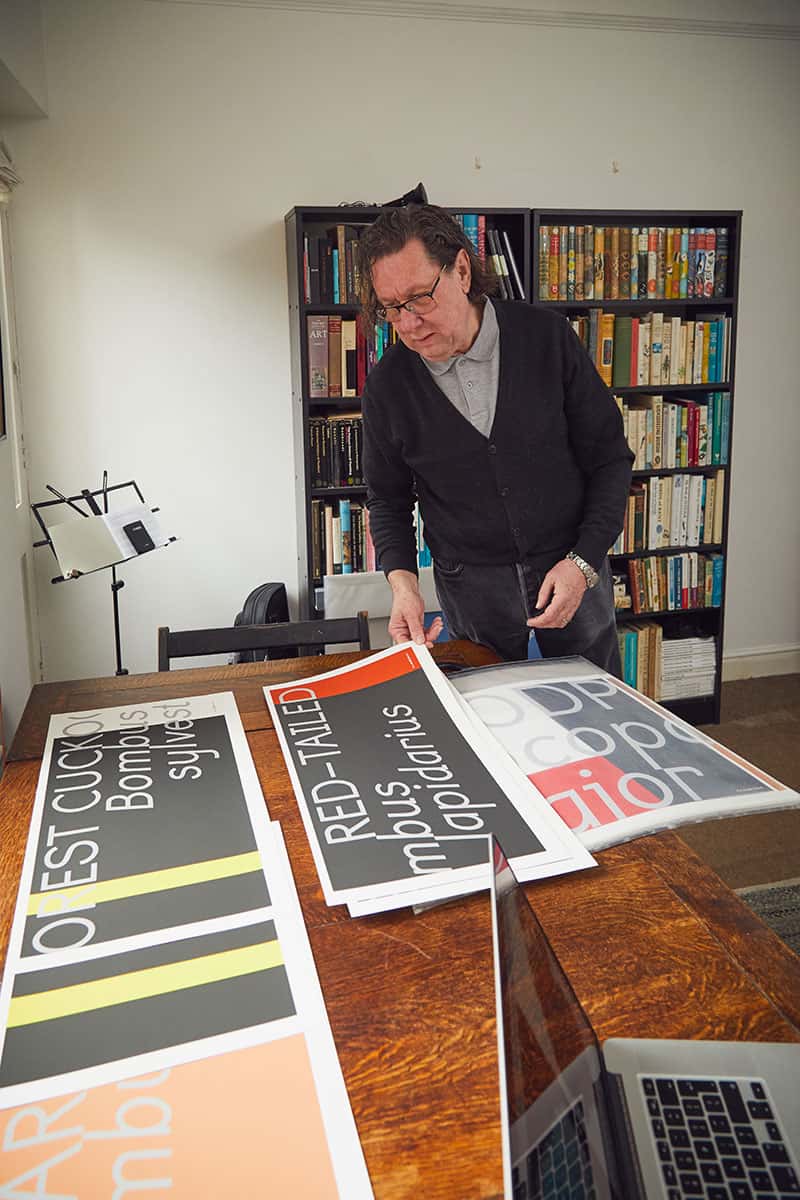 Rob Hillier standing by his typographic work in his home-made Norwich studio