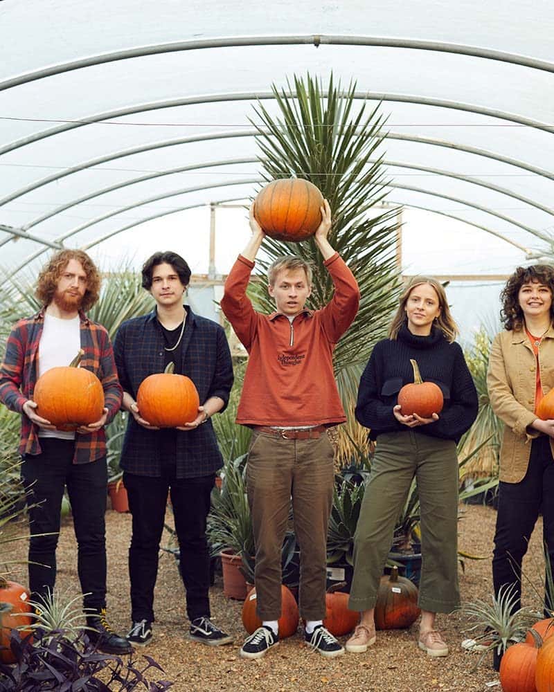 Wild Paths students stand in Urban Jungle Norwich with pumpkins for a Norwich University of the Arts photoshoot