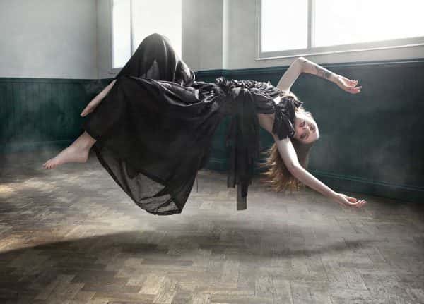 Annabel Leech, MA Fashion. Photography by Kev Foster.  - Photograph of a woman levitating, wearing a black dress and reclining backwards in the air