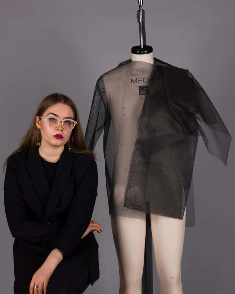 BA Fashion student Eli Kiko sat in front of a draped mannequin at Norwich University of the Arts