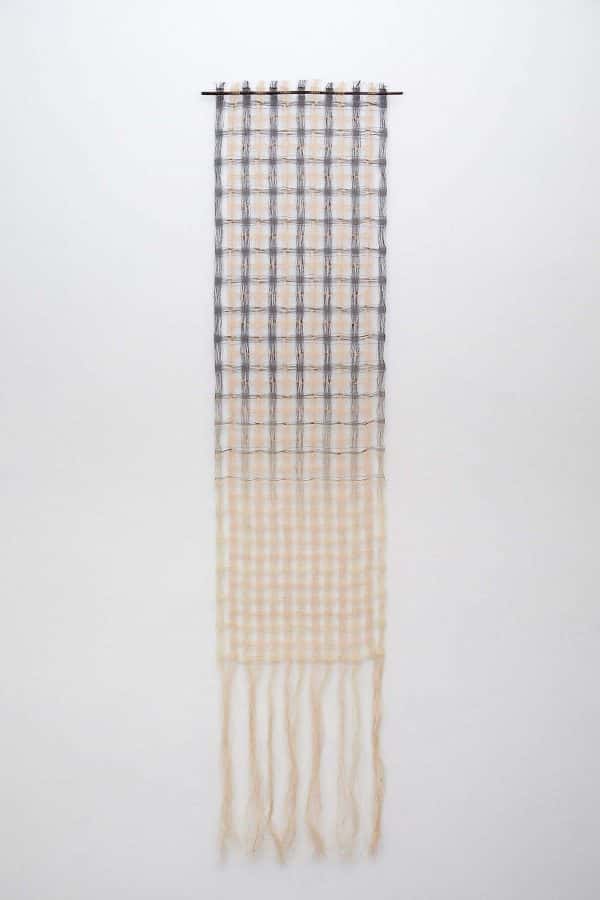 Lizzie Kimbley - Long rectangular textiles piece hanging on a white wall, made of woven squares in cream and blue