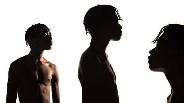 Amy Paske - A black male model is topless, photographed three times against a pure white background, in half and full shadow. From left to right, he faces to the front right, to the right profile, and then facing left. By BA Fashion Communication and Promotion student Amy Paske