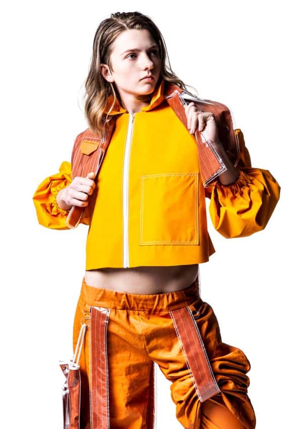 Megan Grinham - White female model wearing a jacket, crop top and cargo trousers in different shades of bright orange. The outfit is inspired by construction workers and is designed by BA Fashion student Megan Grinham