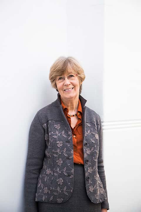 Professor Marcia Pointon standing against a wall at Norwich University of the Arts wearing a jacket