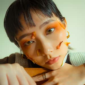 BA Fashion Communication and Promotion work by Gigi Soh showing photographs of a person with orange eyeshadow and petals on their face